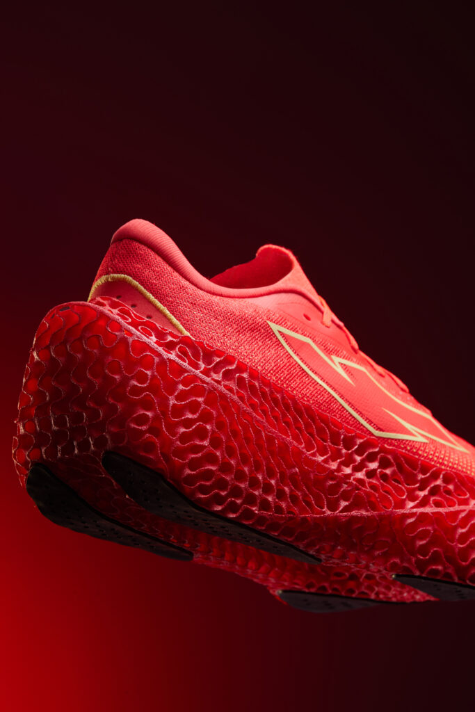Detalle lateral de la Kiprun KipNext 3D roja, con upper textil, logotipo Kiprun y mediasuela 3D de estructura abierta.