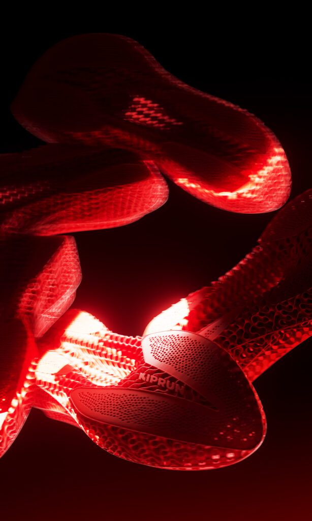Varias Kiprun KipNext 3D rojas iluminadas sobre fondo oscuro, mostrando la mediasuela impresa en 3D y el diseño tipo lattice.